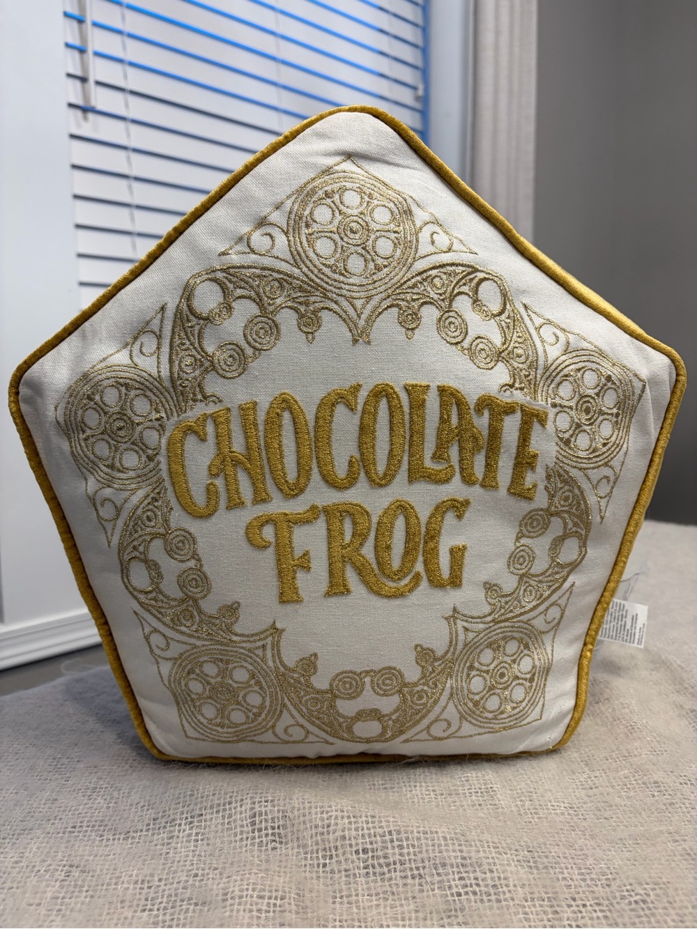 Harry Potter Hallmark chocolate frog pillow in gold/ white.